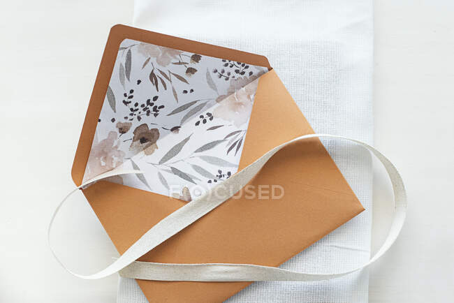 Floral lined envelope with a ribbon on a table — Stock Photo