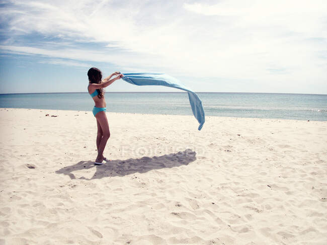 Menina de pé na praia tremendo sua toalha, Maldivas — Fotografia de Stock