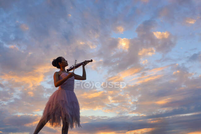 Femme debout à l'extérieur au coucher du soleil jouant du violon, Thaïlande — Photo de stock