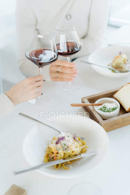 Two women making a celebratory toast with red wine in a restaurant — Stock Photo