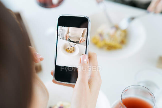 Mulher tirando uma foto de sua comida em um restaurante — Fotografia de Stock
