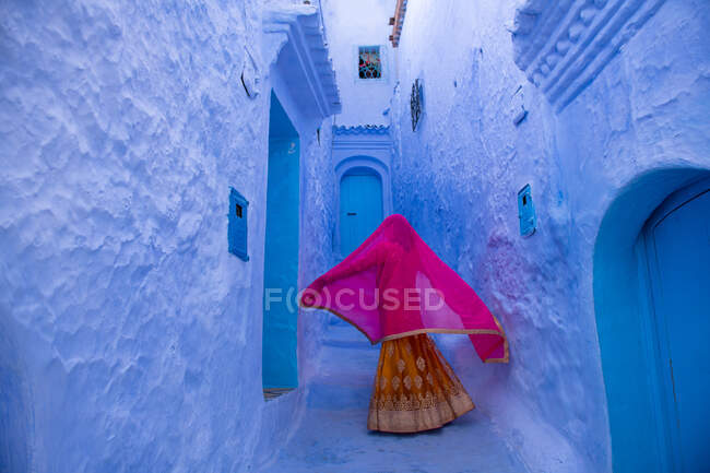 Задний вид на женщину, идущую вдоль городской улицы, Chefchaouen, Марокко — стоковое фото