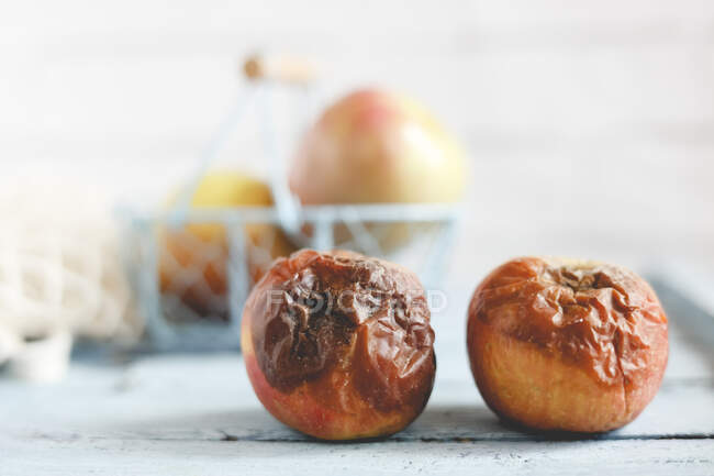 Due mele marce su un tavolo accanto a mele mature fresche — Foto stock