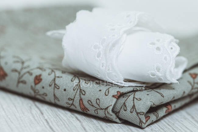 Lace napkin folded on a floral piece of fabric — Stock Photo