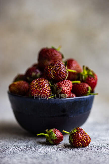 Bowl of fresh strawberries on concrete surface — Stock Photo