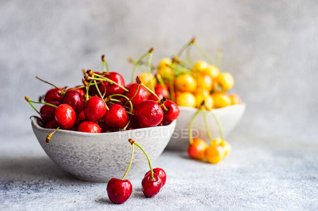 Duas taças de cerejas vermelhas e amarelas — Fotografia de Stock
