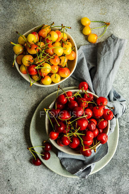 Top view of bowls of red and yellow cherries with cloth napkin — Stock Photo