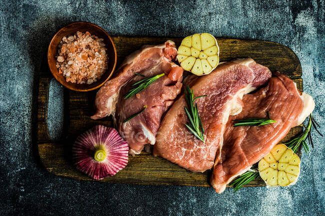 Top view of raw pork steaks with garlic, rosemary and pink himalayan salt — Stock Photo