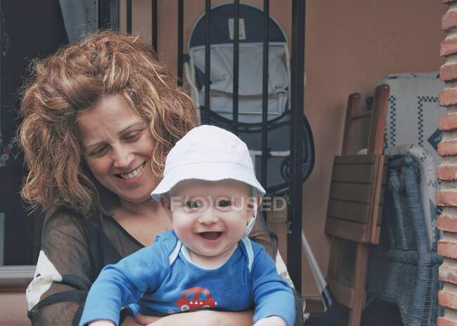 Porträt eines kleinen Jungen, der auf dem Schoß seiner Mutter auf einer Terrasse sitzt — Stockfoto