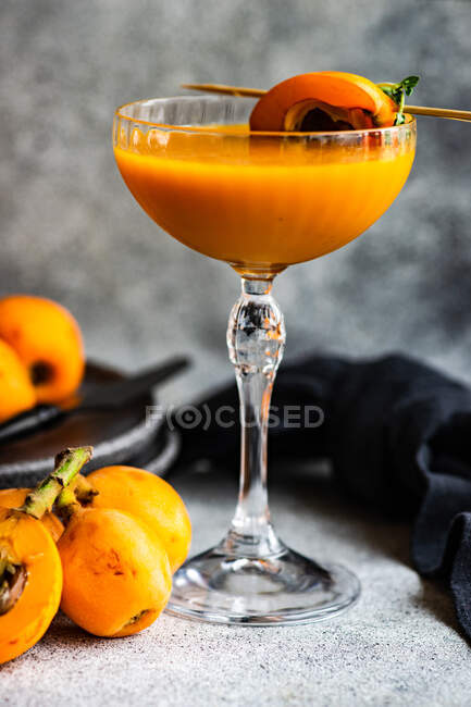 Fruit juice in elegant glass with fresh loquats — Stock Photo