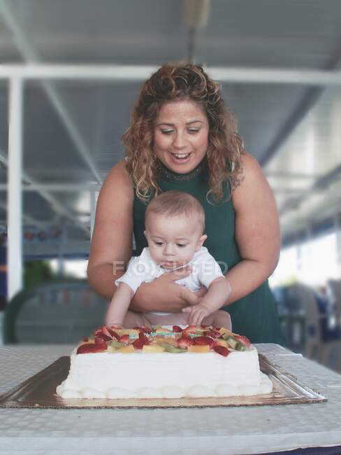 Madre in piedi davanti a una prima torta di compleanno con suo figlio — Foto stock