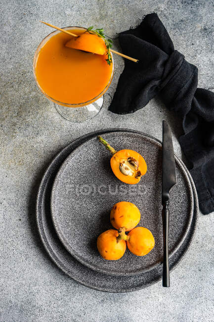 Overhead view of loquat fruits and fruit juice on a plate — Stock Photo
