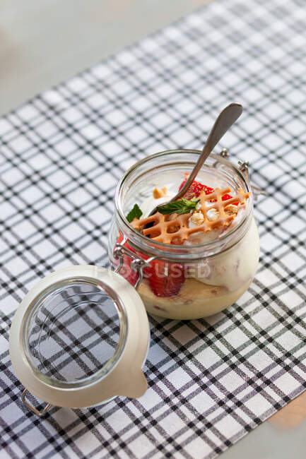 Ice cream, strawberries and a wafer in a glass jar on a table — Stock Photo