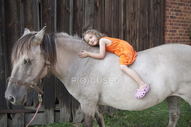 Улыбающаяся девочка, лежащая на коне, Польша — стоковое фото