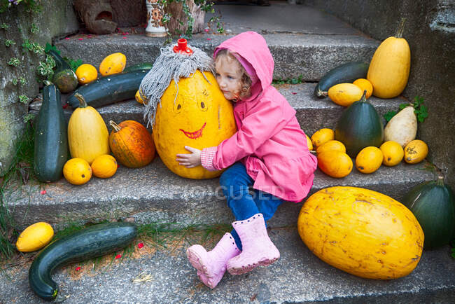 Дівчинка сидить на сходах, обіймаючи гарбуз восени, Польща. — стокове фото