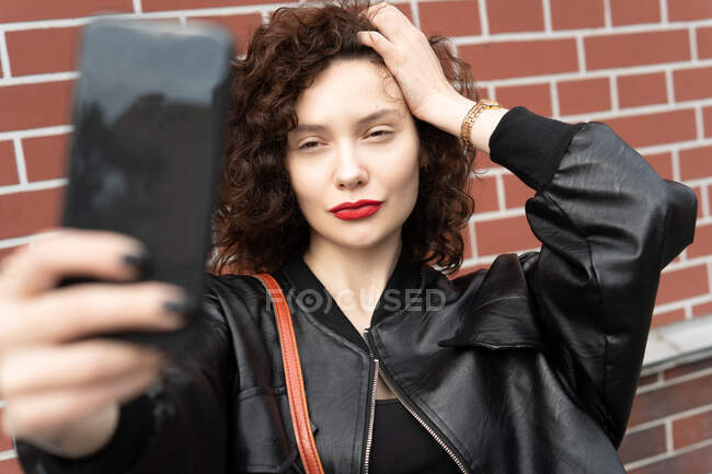Beautiful woman standing in street taking a photo of herself — Stock Photo