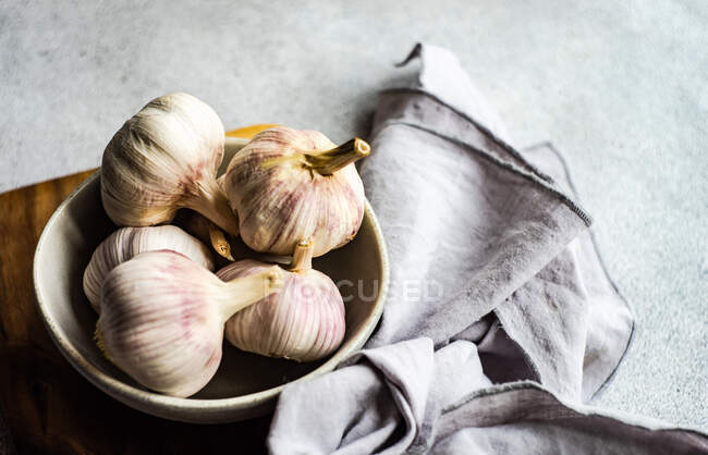 Raw garlic gloves in the bowl on stone background — Stock Photo