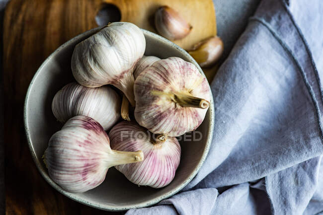 Raw garlic gloves in the bowl on stone background — Foto stock