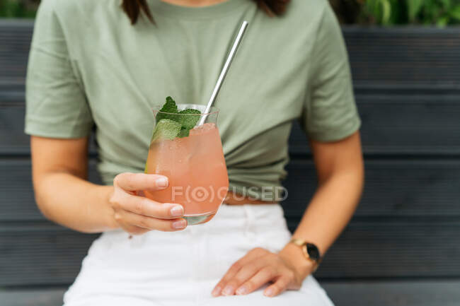 Portrait of a woman with holding a paloma cocktail sitting on a bench — Stock Photo