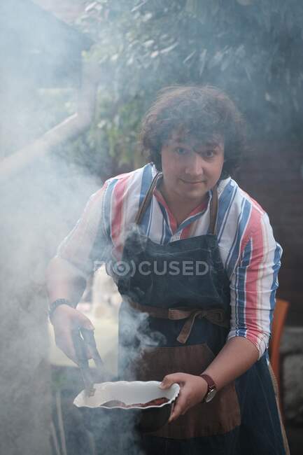 Retrato de um homem cozinhando salsichas em um churrasco — Fotografia de Stock