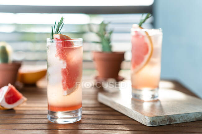 Два стакана воды со свежим грейпфрутом и грейпфрутом на столе — стоковое фото