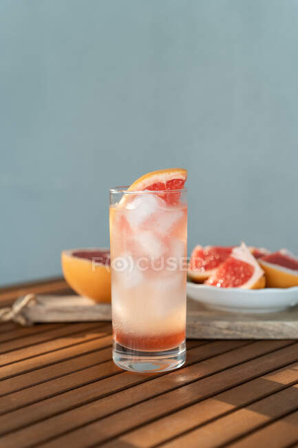 Glass of water with fresh grapefruit and grapefruit segments on a table — Stock Photo