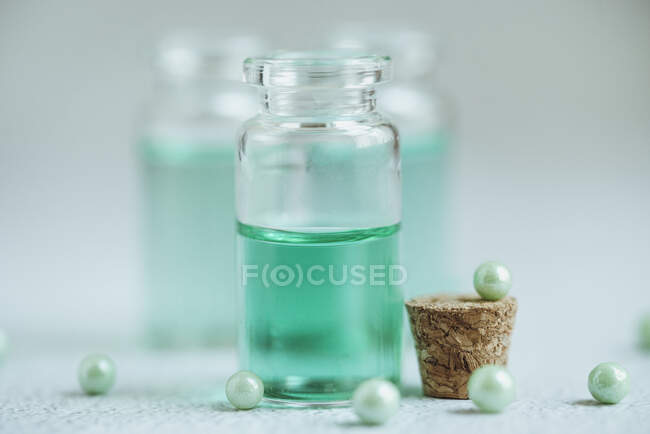 Бутылки зеленой жидкости и зеленый жемчуг на столе — стоковое фото