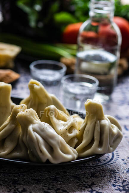 Traditional georgian supra with khinkali, vegetable set and chacha drink in glasses — Stock Photo