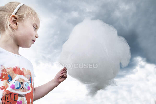 Portrait of a girl holding candy floss that looks like a cloud, Poland — Stock Photo