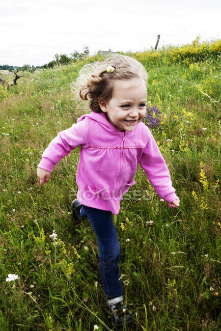 Smiling girl running through a meadow, Poland — Stock Photo