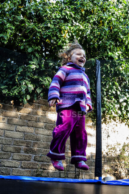 Ragazza felice che salta su un trampolino in giardino — Foto stock