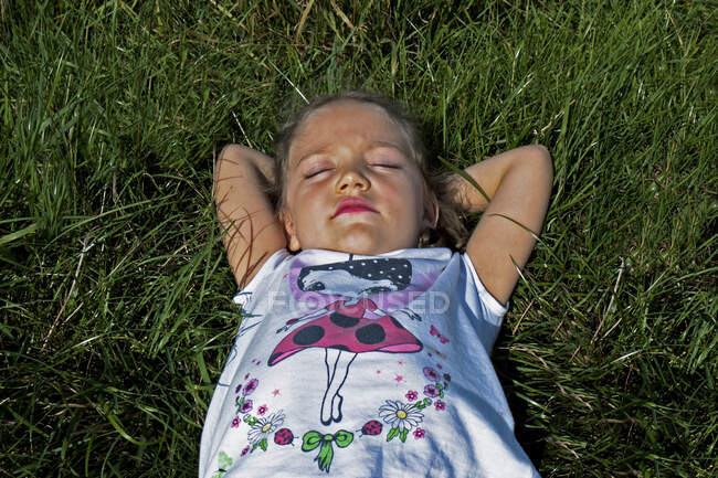 Над головою відкривається вид на дівчину, яка лежить на луці на літньому сонці (Польща). — стокове фото