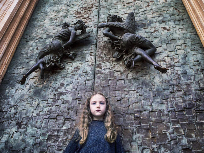 Retrato de una niña de pie frente a las puertas de la iglesia, Italia - foto de stock