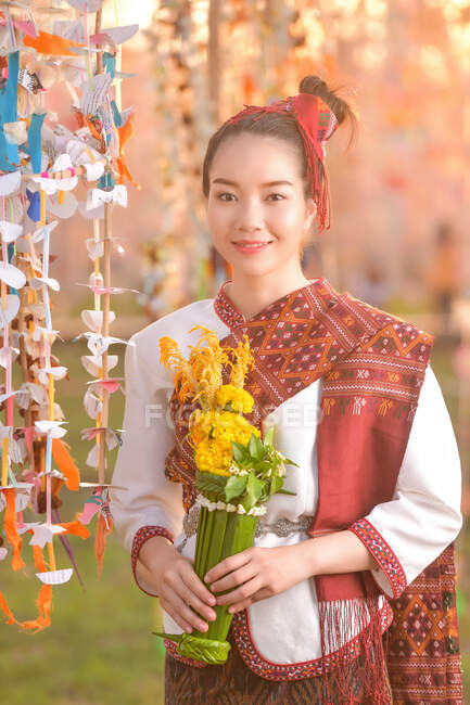 Portrait of a smiling woman in traditional Thai clothing holding flowers, Thailand — Stock Photo