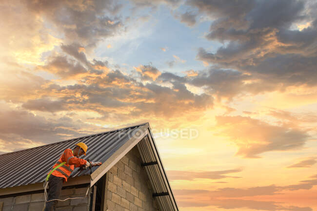 Construction worker installing metal sheets on a roof, Thailand — Stock Photo