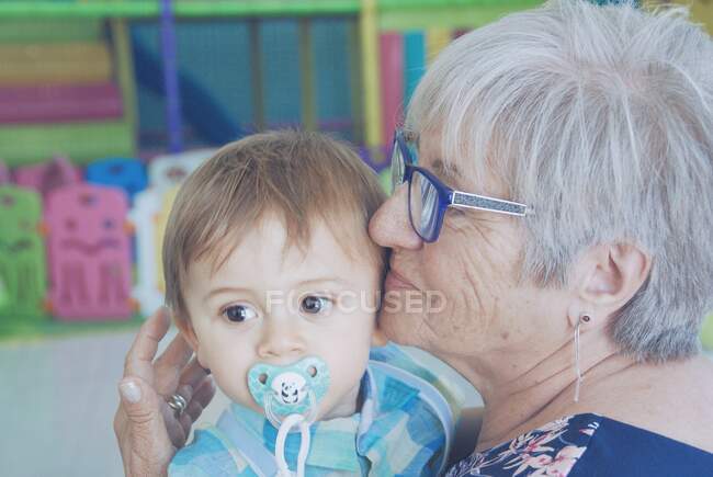 Porträt einer Großmutter, die ihren Enkel kuschelt — Stockfoto