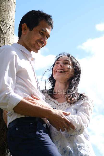 Retrato de una pareja feliz apoyada en un árbol, Francia - foto de stock