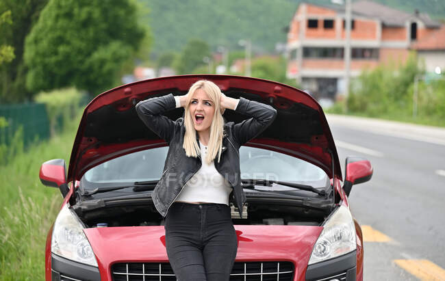Frau lehnt auf Motorhaube ihres kaputten Autos, Bosnien und Herzegowina — Stockfoto