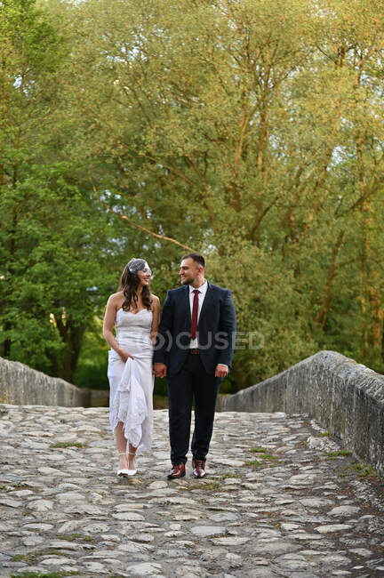 Porträt eines frisch verheirateten Paares, das über eine Brücke geht — Stockfoto