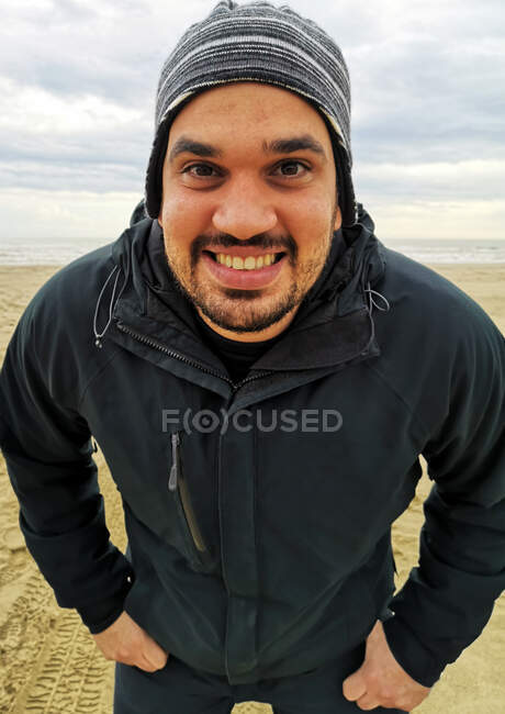 Porträt eines lächelnden Mannes, der mit den Händen in den Taschen am Strand steht, Apulien, Italien — Stockfoto
