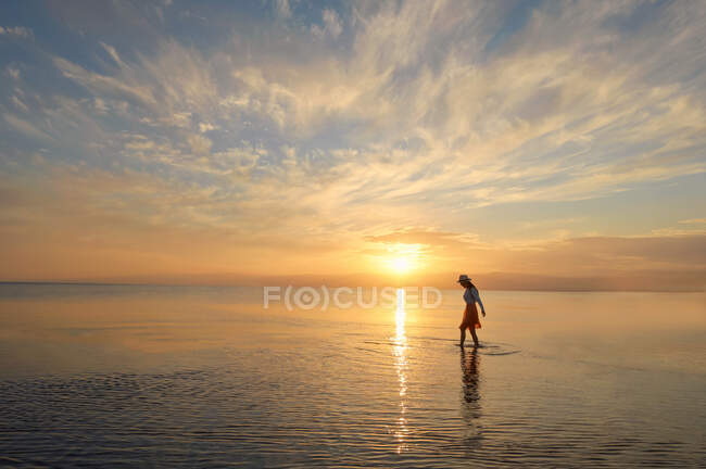 Femme marchant dans l'océan au coucher du soleil, Thaïlande — Photo de stock