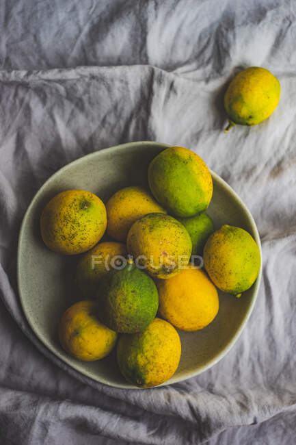 Ciotola di gres pieno di limoni organici su sfondo tessile — Foto stock