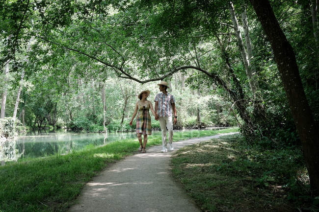 Joyeux couple marchant sur un long sentier au bord d'une rivière en été, France — Photo de stock