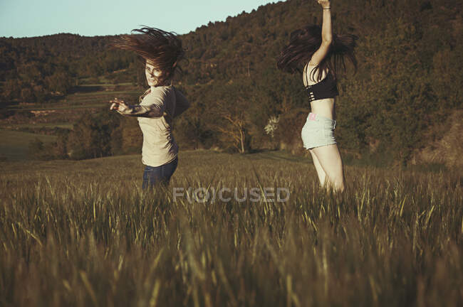 Madre e hija bailando en un campo en verano, España - foto de stock