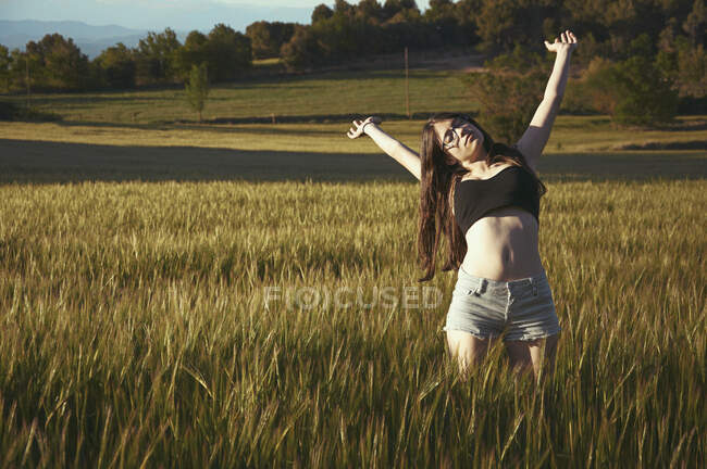 Adolescente debout dans la prairie avec les bras tendus, Espagne — Photo de stock