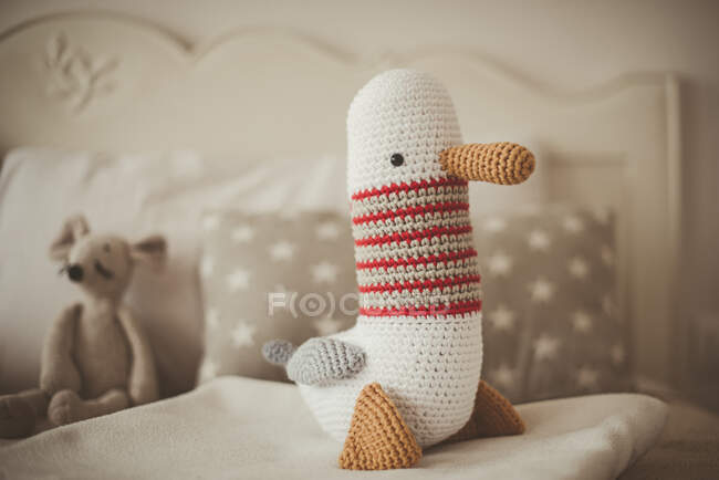 Petit canard tricoté jouet sur le lit — Photo de stock