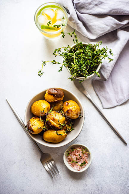 Deliciosas batatas novas em uma tigela polvilhada com erva de tomilho picada servida em uma mesa de concreto — Fotografia de Stock