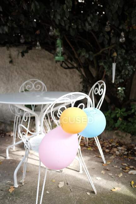 Three birthday balloons tied to garden chair — Stock Photo
