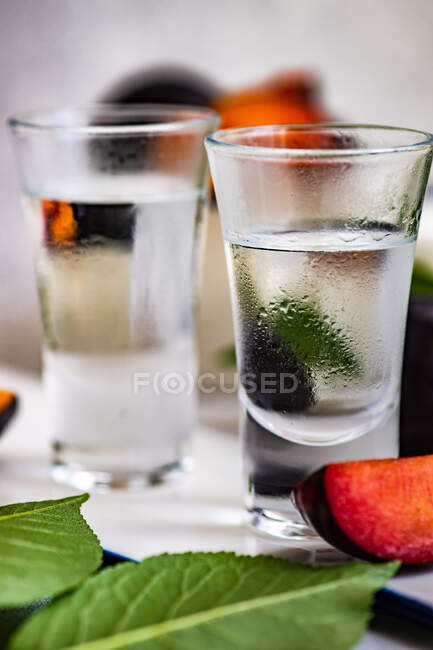 Vodka di prugna servita in bicchieri freddi e prugne fresche su un tavolo — Foto stock