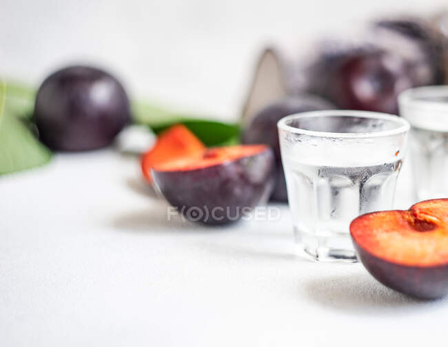 Vodka de ciruela servido en vasos fríos y ciruelas frescas sobre una mesa - foto de stock